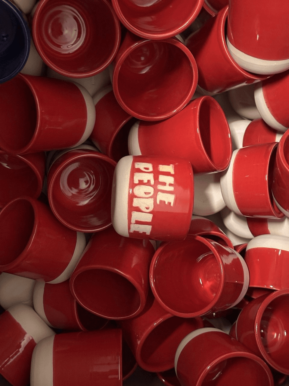 Czerwone ceramiczne czarki z jasną podstawą i napisem THE PEOPLE