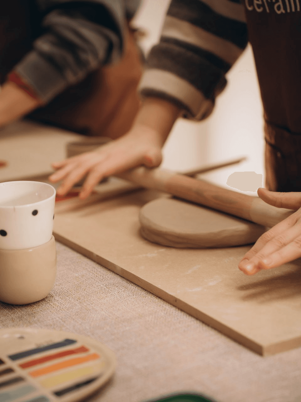 Dłonie rozwałkowujące glinę podczas warsztatów ceramicznych